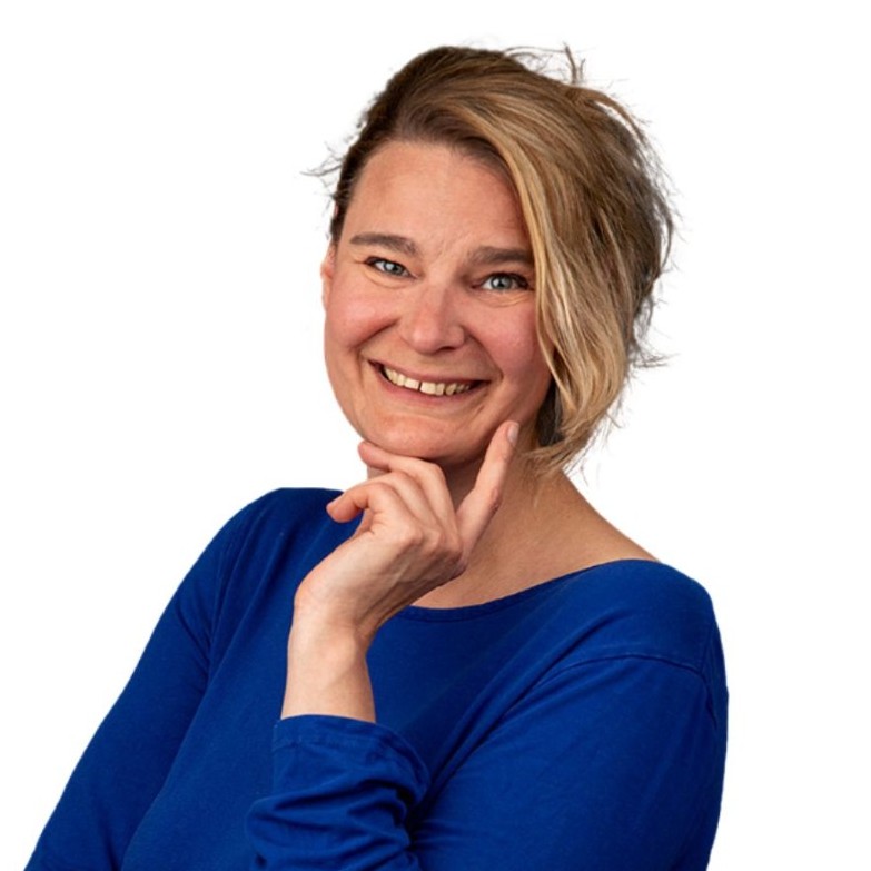 Das Bild zeigt Susanne Salomon im Halbprofil. Sie hat die Hand am Kinn und die blonden und braunen Haare in einer Welle. Sie trägt einen blauen Pullover.