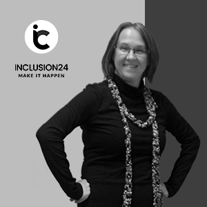 Foto von Izabella Pawliczek. Sie steht, hat die Hände in die Seiten gestützt und lacht in die Kamera. Sie hat einen schwarzen Pullover an und einen Schal um den Hals.