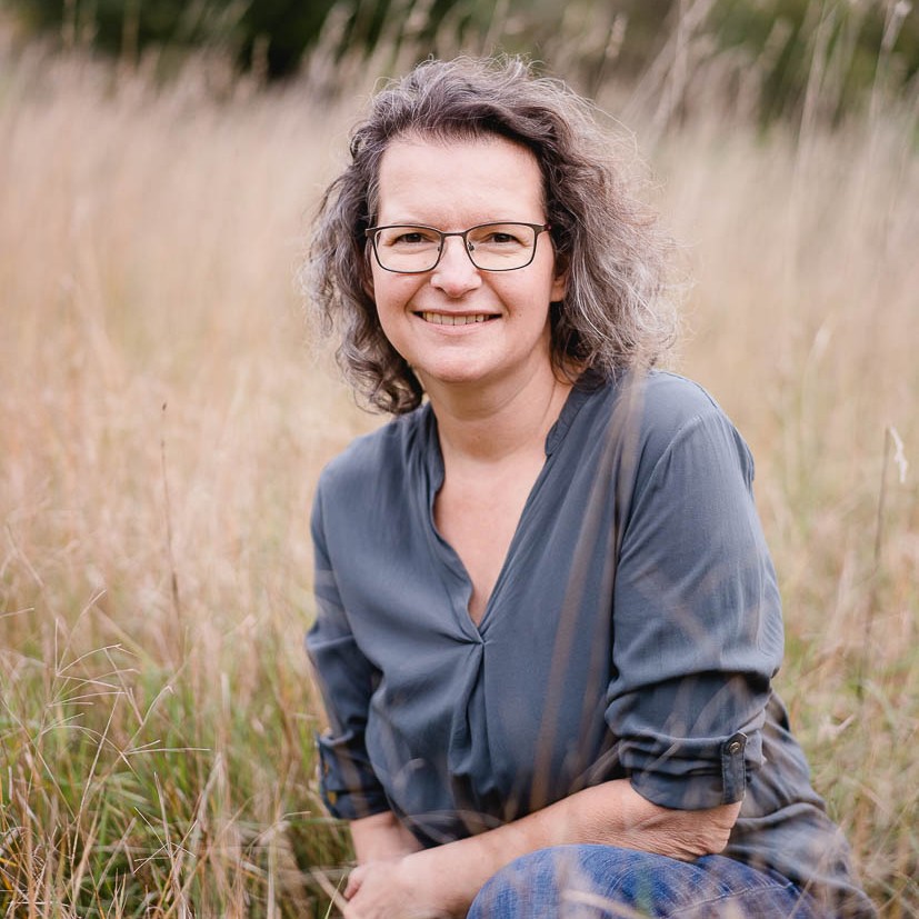 Iris Wagner von vorne fotografiert. Brille, halblange Haare, blaues Kleid